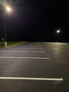 Freshly paved and line-striped parking lot at night under bright overhead lighting.