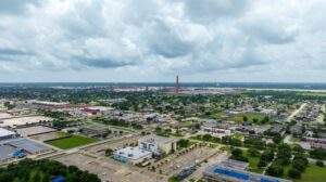 Aerial view of a Louisiana town featuring commercial buildings, residential neighborhoods, and large parking lots under a cloudy sky.
